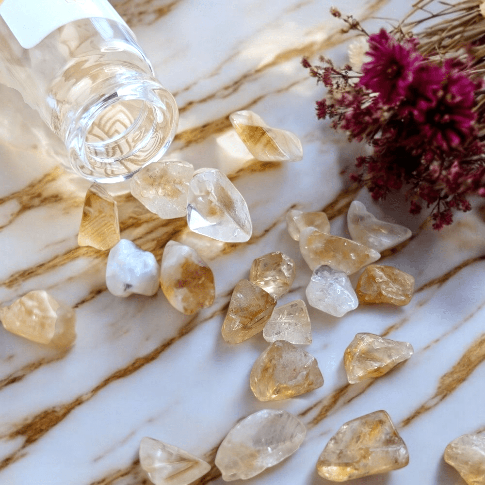 Raw citrine crystals on a marble surface with a bottle and flowers