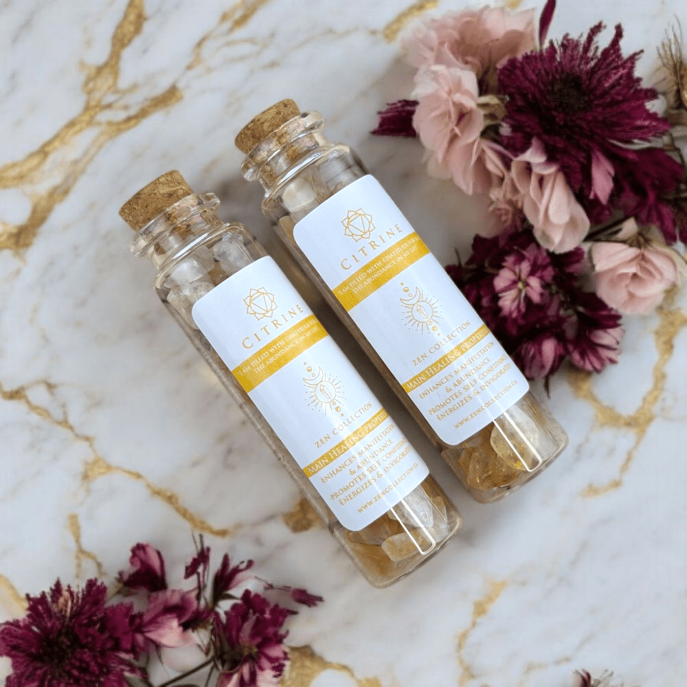 Two glass bottles with cork lids on a marble surface with flowers around