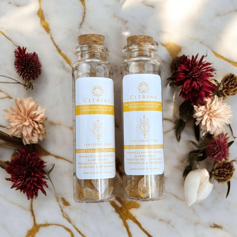 Two glass bottles with citrine crystals ,cork lids on a marble surface surrounded by flowers