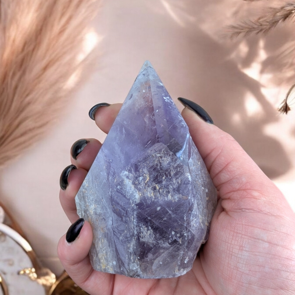 Amethyst Crystal Point with natural inclusions held in hand.