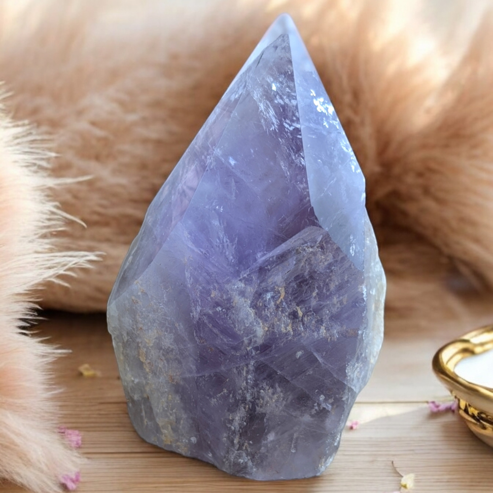 Polished Amethyst Crystal Point against a soft, earthy background.