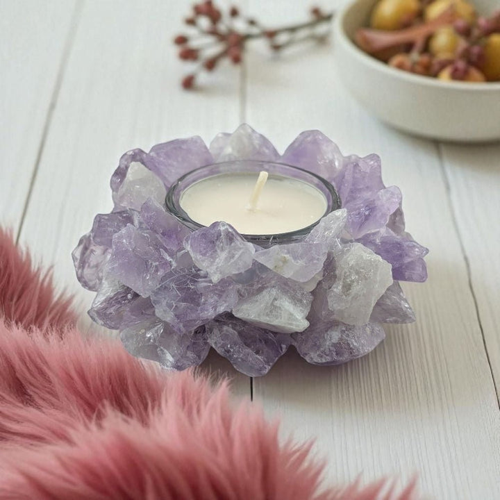 Candle holder made of raw purple amethyst crystals with a candle inside on a light wooden surface.