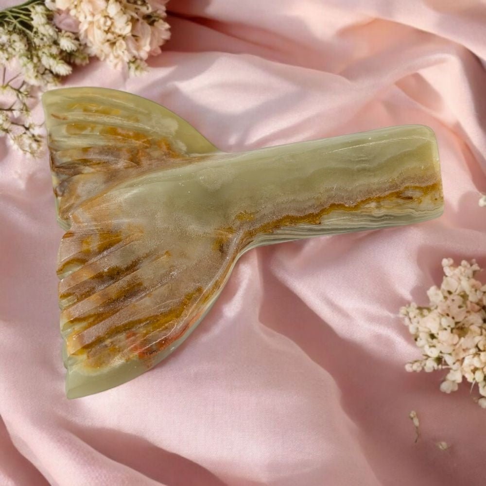 Banded Calcite crystal with a natural pattern on a pink fabric background with flowers.