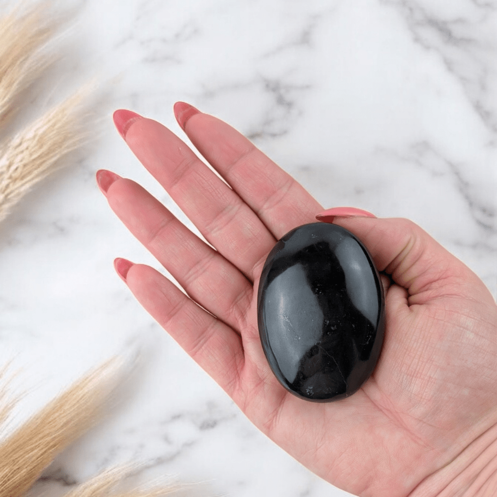 Black Obsidian palm stone in hand
