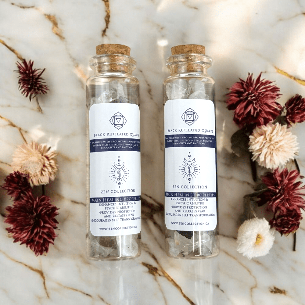 Two glass bottles filled with Black Rutilated Quartz crystals cork lids on a marble surface with flowers around.