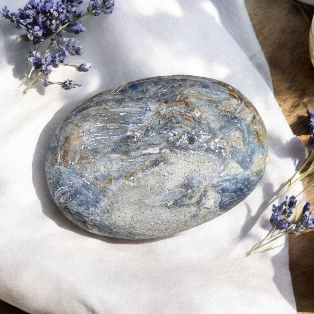 Close-up of Blue Kyanite Crystal Palm Stone with shimmering blue pigments.