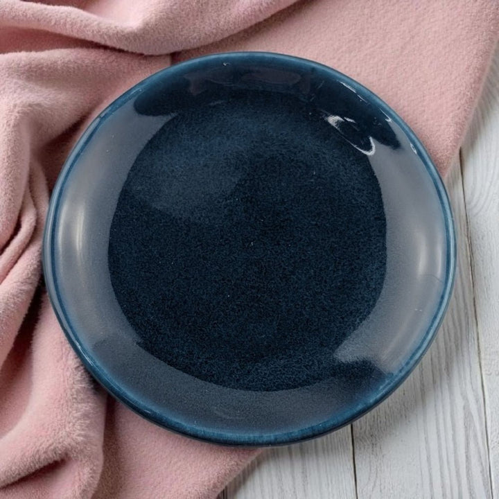 Blue ceramic bowl on a pink fabric background