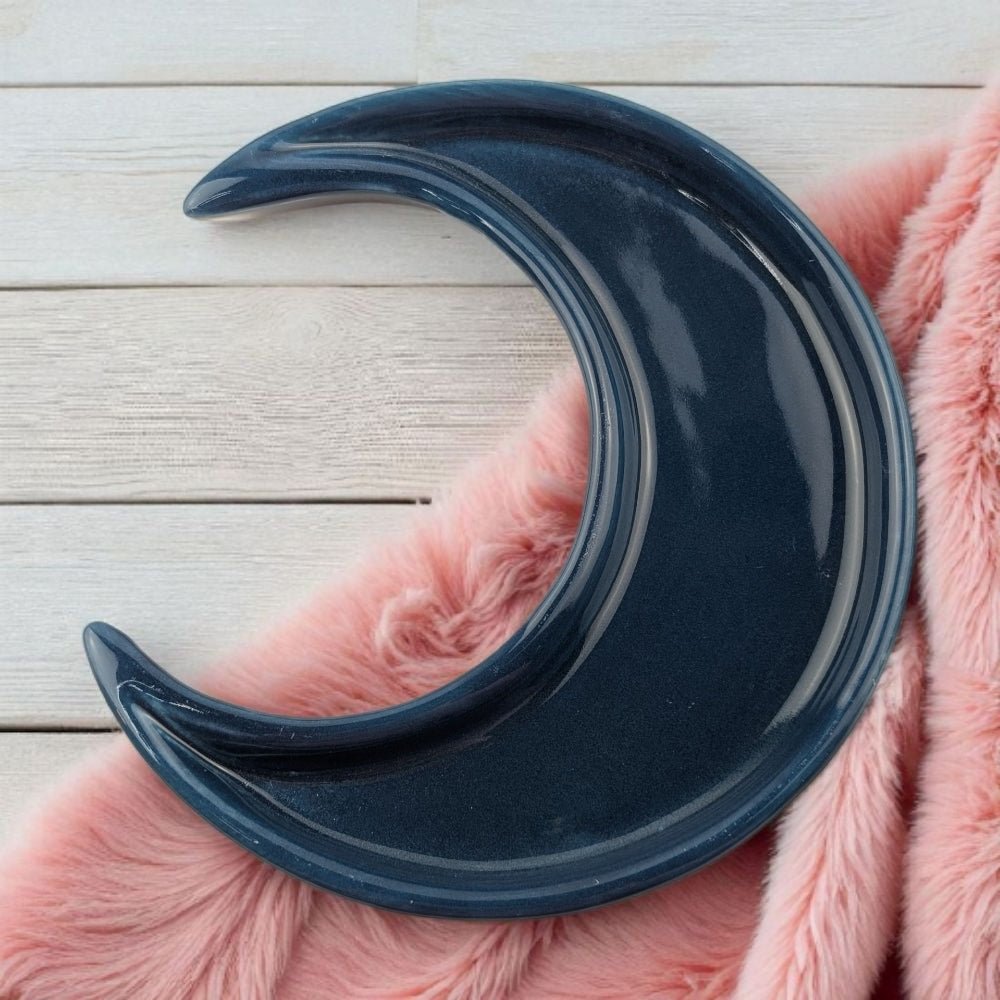 Blue crescent-shaped object on a pink fluffy surface with a light wooden background