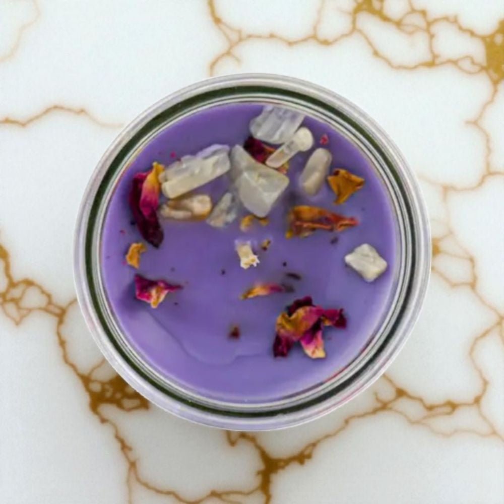 Purple candle in a glass jar with decorative elements on a marble surface