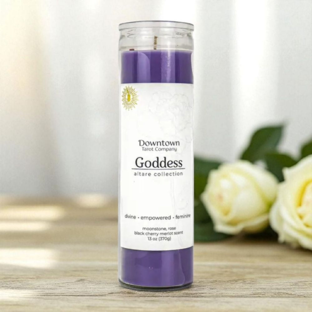 Purple candle with a label on a wooden surface with white flowers in the background