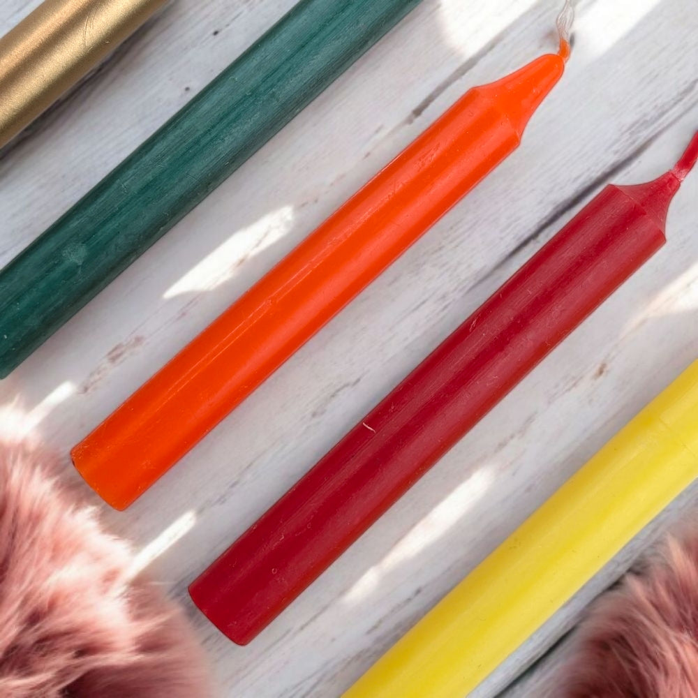 Colorful ritual candles for steady success and humble leadership on a white wooden surface