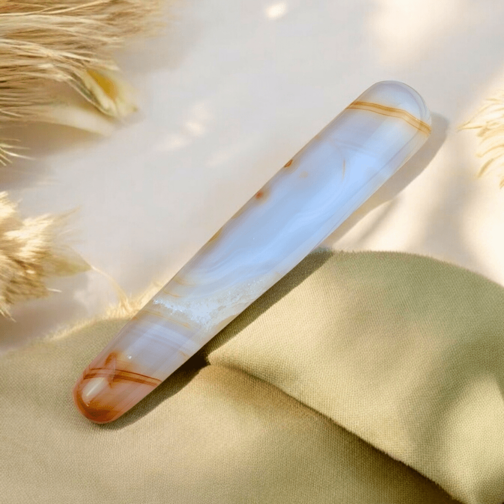 Woman holding a polished carnelian massage wand for personal use.