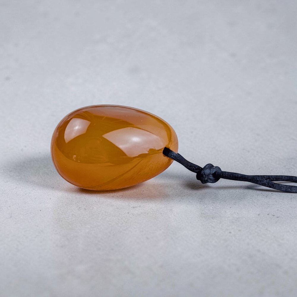 Polished orange carnelian yoni egg close-up.