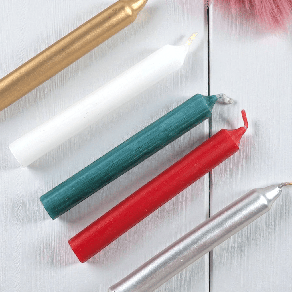 Five colorful Christmas spell candles on a white wooden surface. Available at Zen Collection Metaphysical Stores Barrie