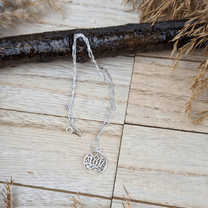 Lotus flower pendant in a silver circle, symbolizing growth and renewal.