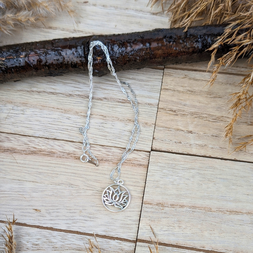 Lotus flower pendant in a silver circle, symbolizing growth and renewal.