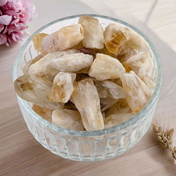 Glass bowl filled with heat treated citrine pieces on a light wooden surface.
