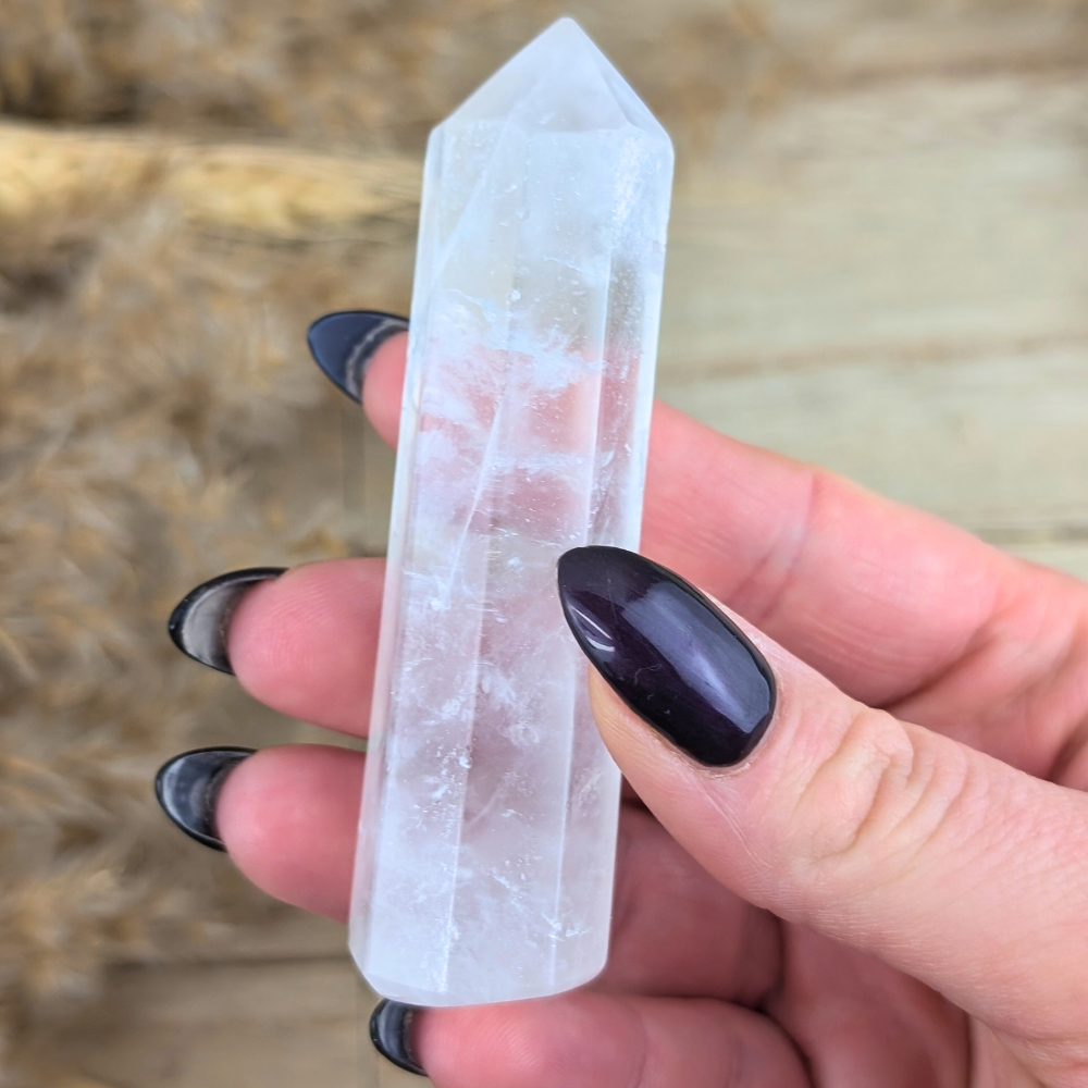 Clear Quartz Point displayed on wood with soft background