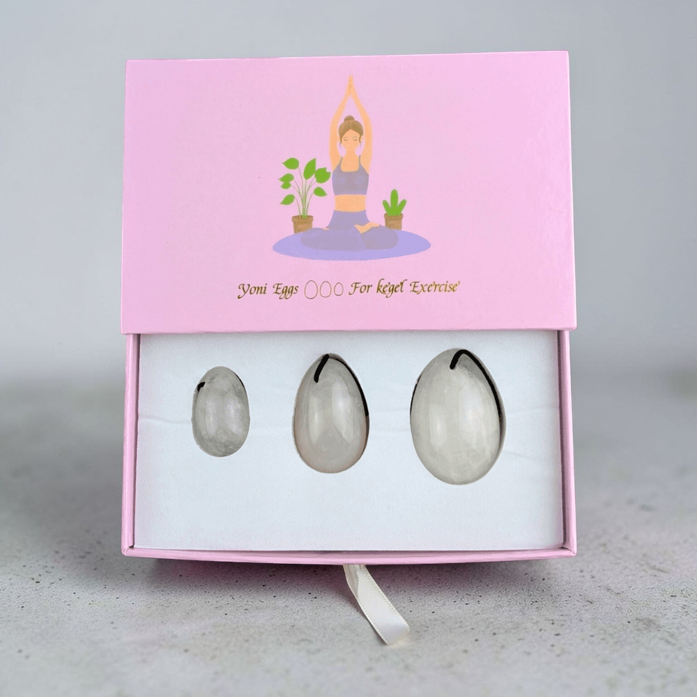 Clear quartz yoni egg set on a soft fabric background.