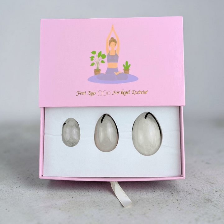 Clear quartz yoni egg set on a soft fabric background.