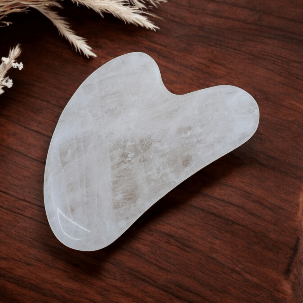 Close-up of a clear quartz gua sha with natural inclusions.