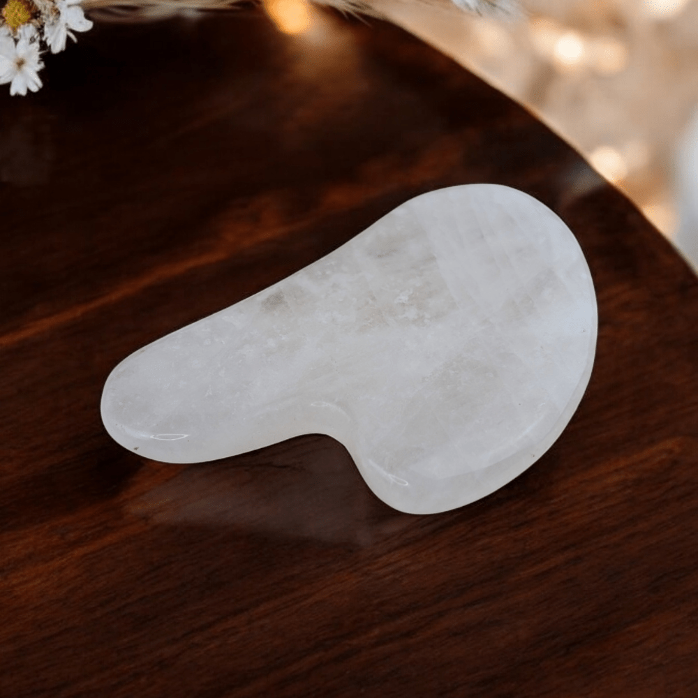 Clear quartz gua sha on soft fabric for relaxation rituals.