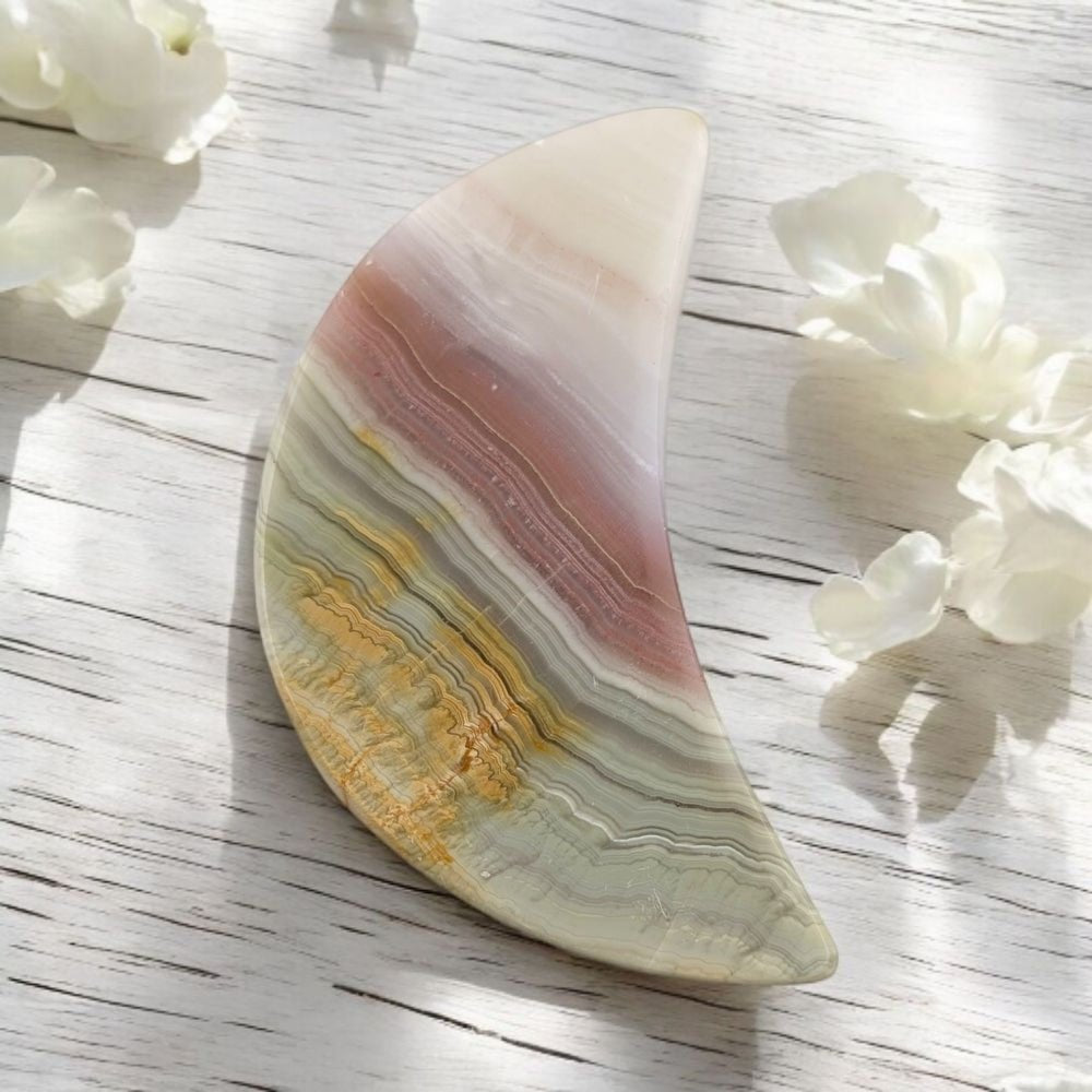 Multicolored calcite stone on a light wooden surface with white flowers