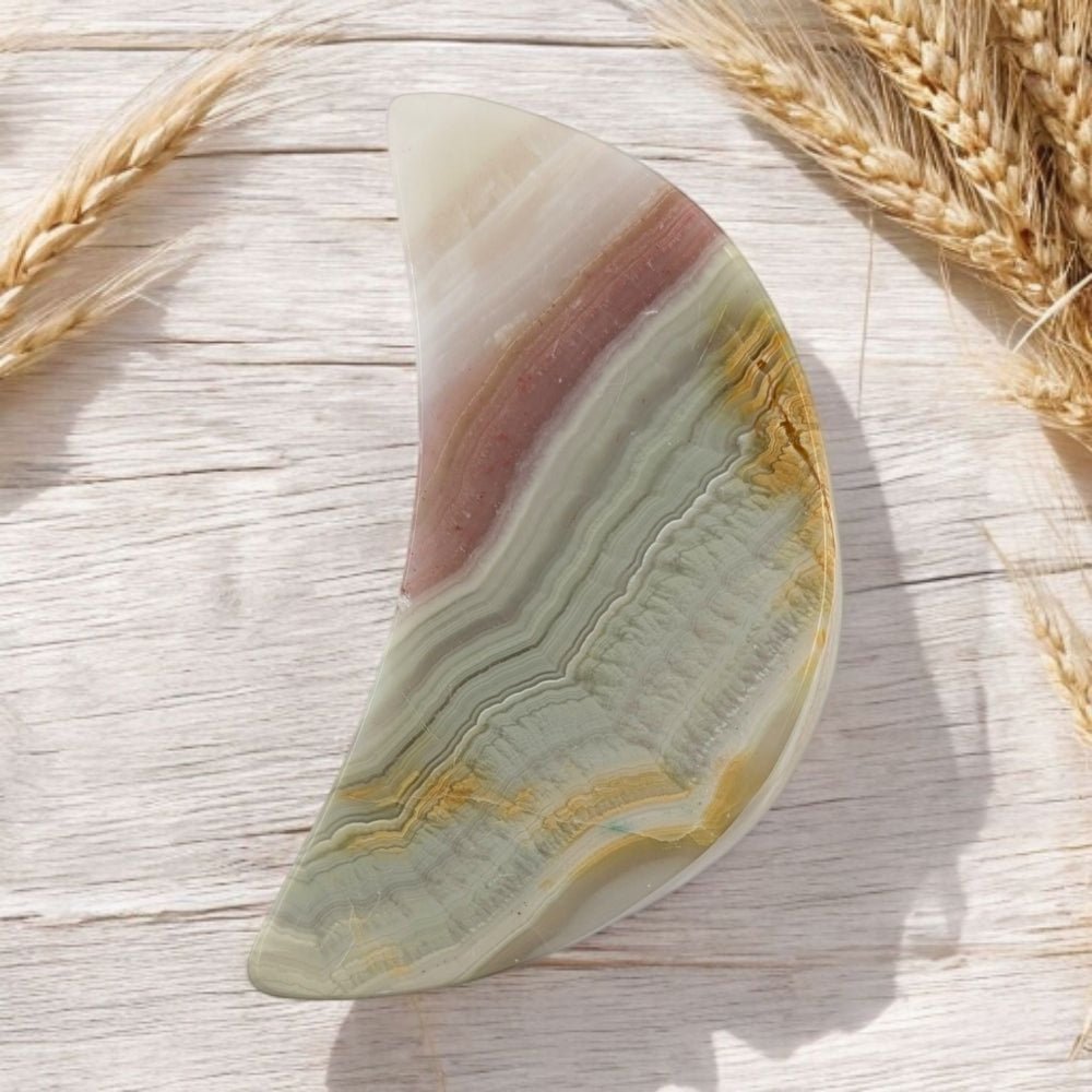 Decorative crystal moon carving with natural patterns on a wooden surface with wheat stalks.