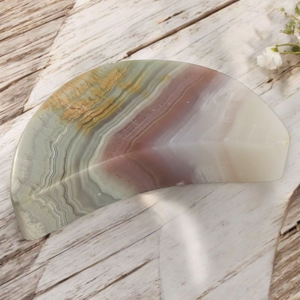 Polished crystal moon with multicolored patterns on a wooden surface