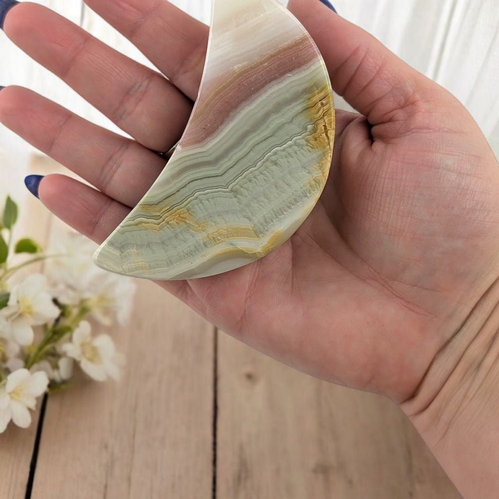 Hand holding a semi-precious calcite stone with floral background