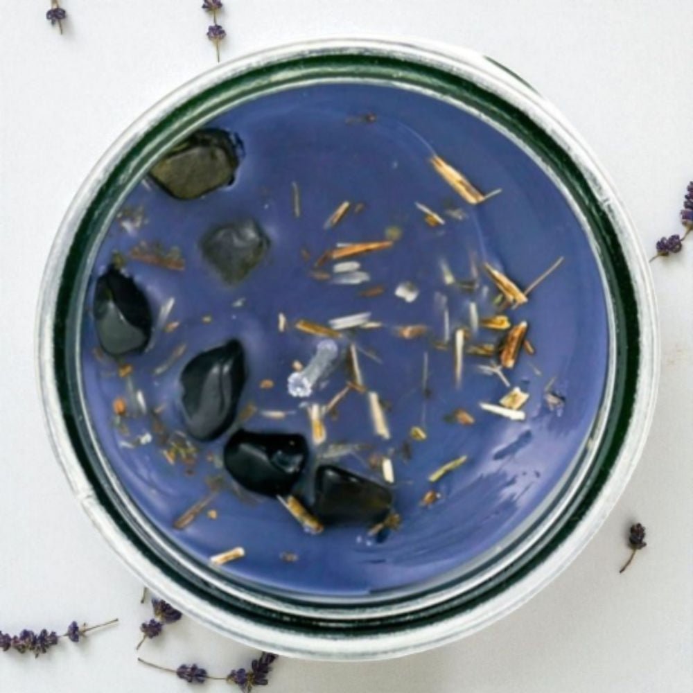 Black candle in a glass jar with with crystals on a white background