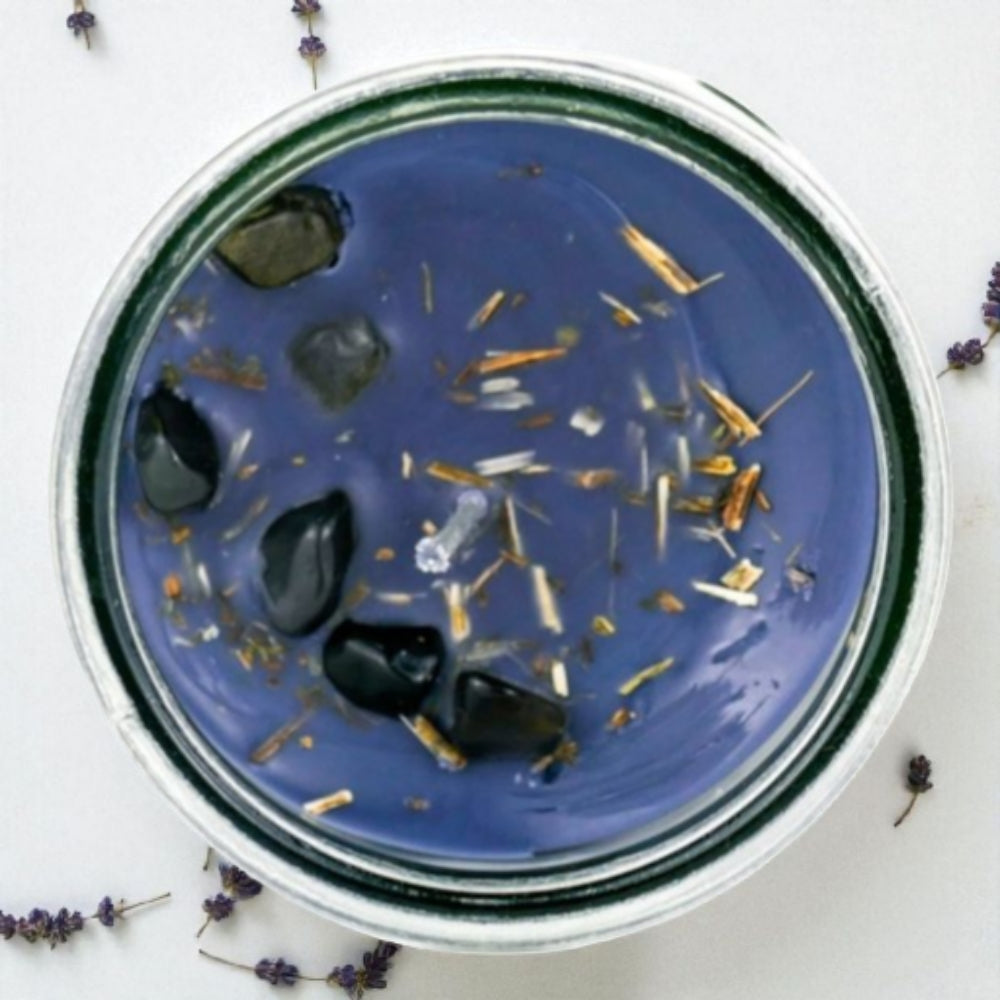 Black candle in a glass jar with with crystals on a white background