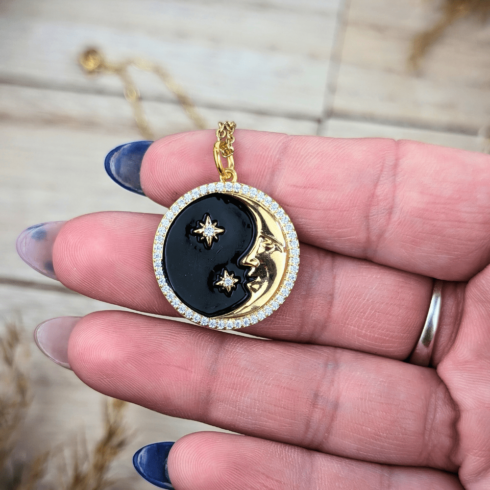 Black enamel and brass moon and star pendant, symbol of cosmic connection and night’s mystery.