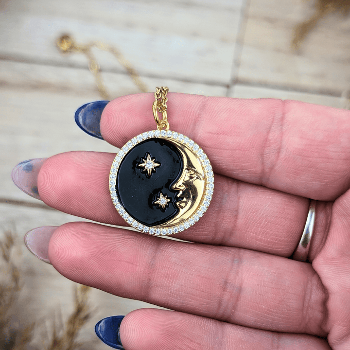 Black enamel and brass moon and star pendant, symbol of cosmic connection and night’s mystery.