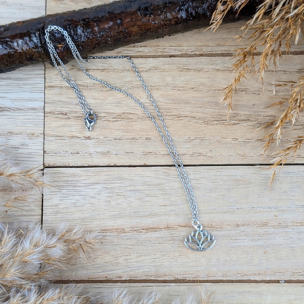 Silver-tone lotus necklace displayed on a natural wooden surface