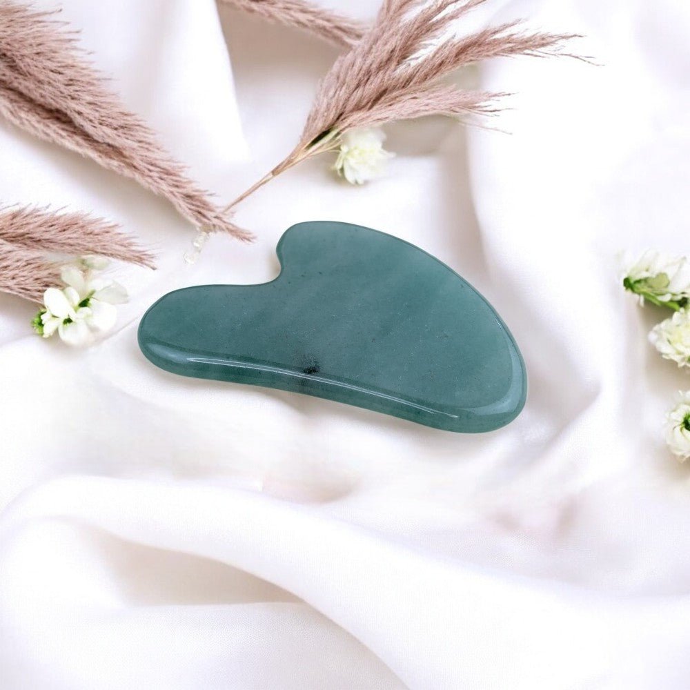 Natural green aventurine gua sha with mineral inclusions.