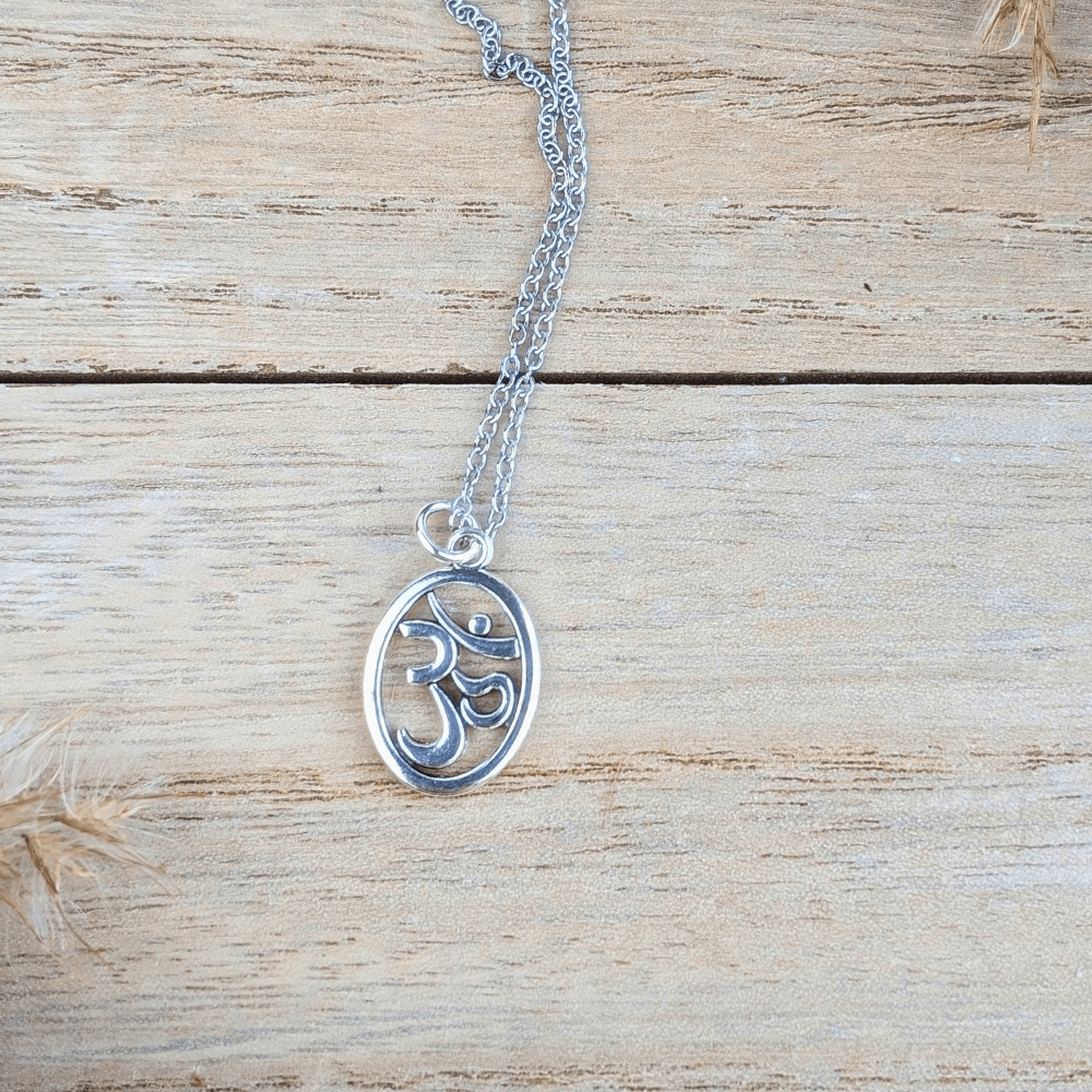Close-up of the silver Om symbol necklace displayed on a wooden surface.