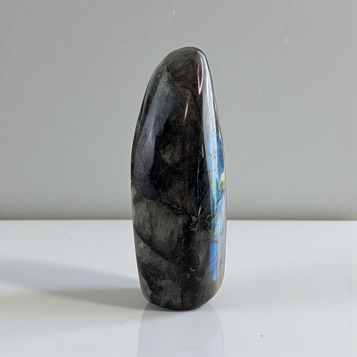 Polished labradorite stone for third eye chakra on a white surface with a gray background. Shop In-store or Online Now with Zen Collection Metaphysical Store in Barrie Ontario Canada 