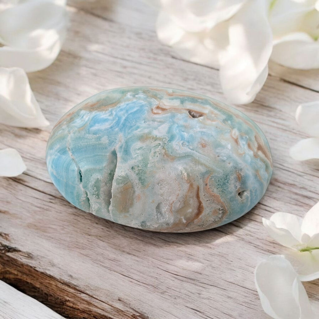 Marbled blue aragonite stone on a wooden surface with white flowers