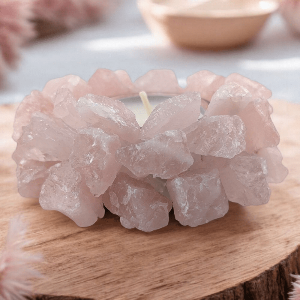 Candle with a pink rose quartz crystal design on a wooden surface