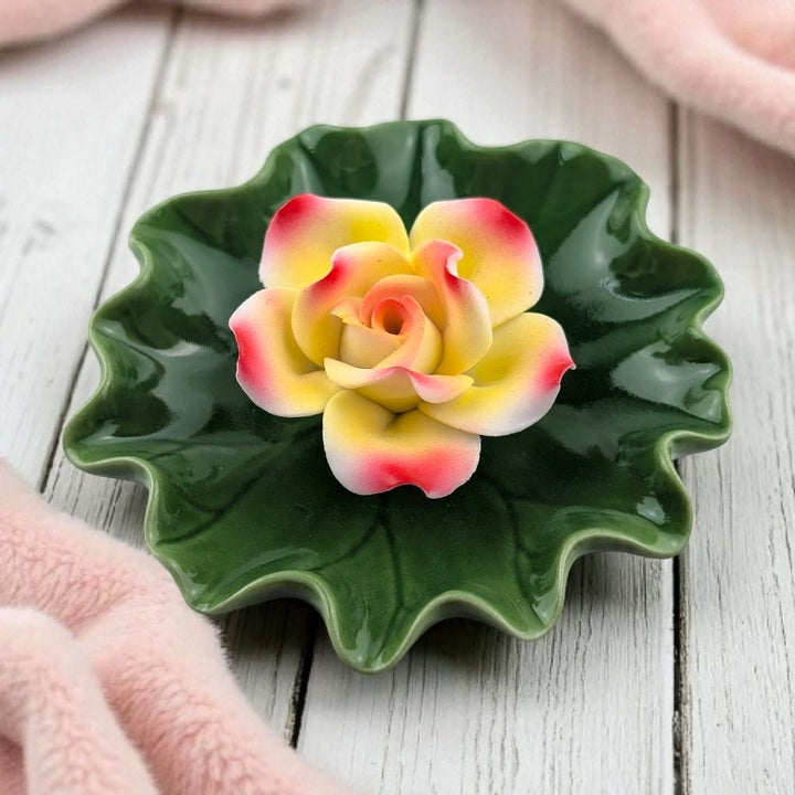 Ceramic lotus flower incense burner and dish with a colorful flower on a wooden surface