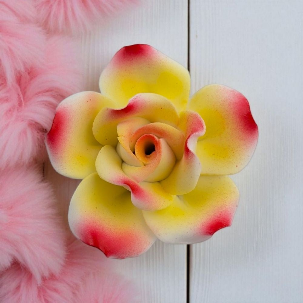 Decorative  lotus flower with yellow and red petals on a white wooden surface