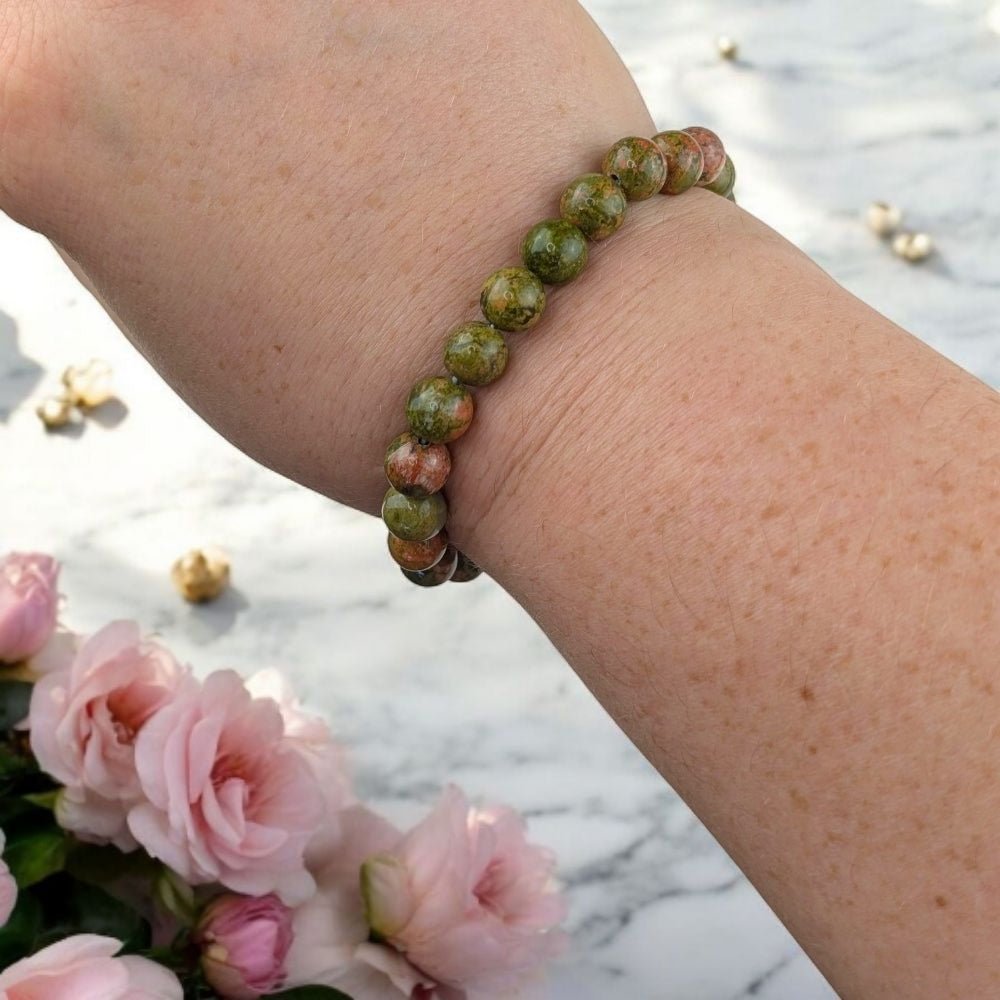 Fertility support crystal bracelet on a wrist with pink flowers in the background