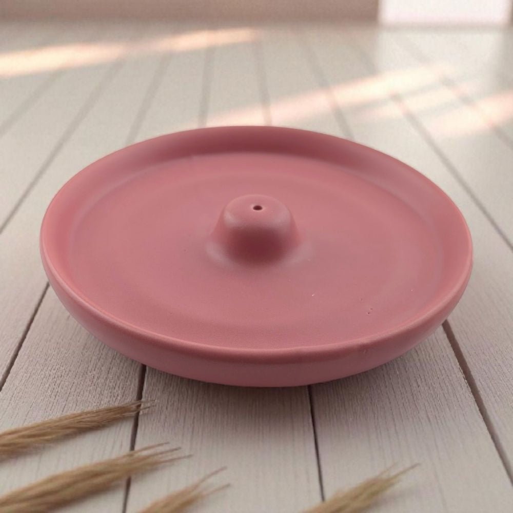 Pink ceramic mess free incense burner on a wooden surface with dried grasses.