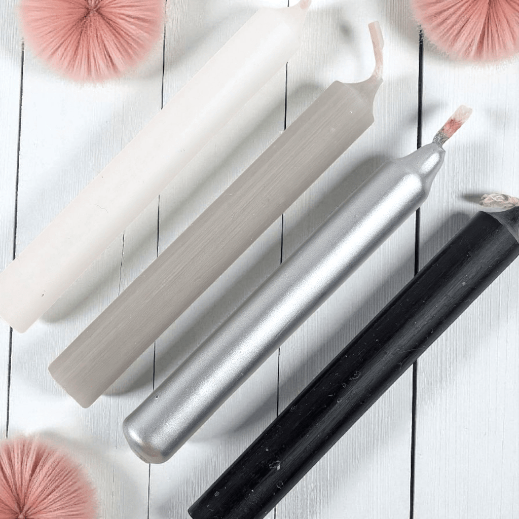 Set of metallic spell candles on a wooden surface with decorative pink pom-poms. available in-store at our crystal store or 24/7 online