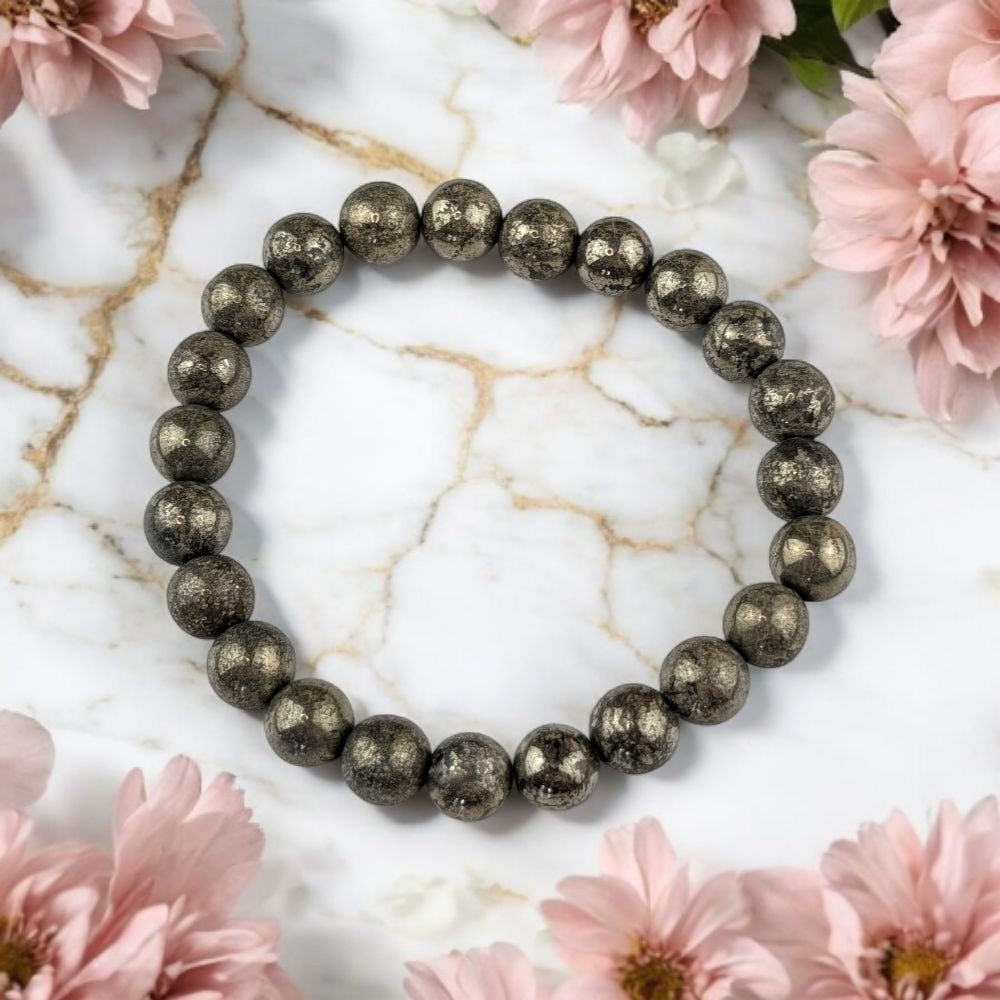 Pyrite beaded bracelet on a marble surface with pink flowers
