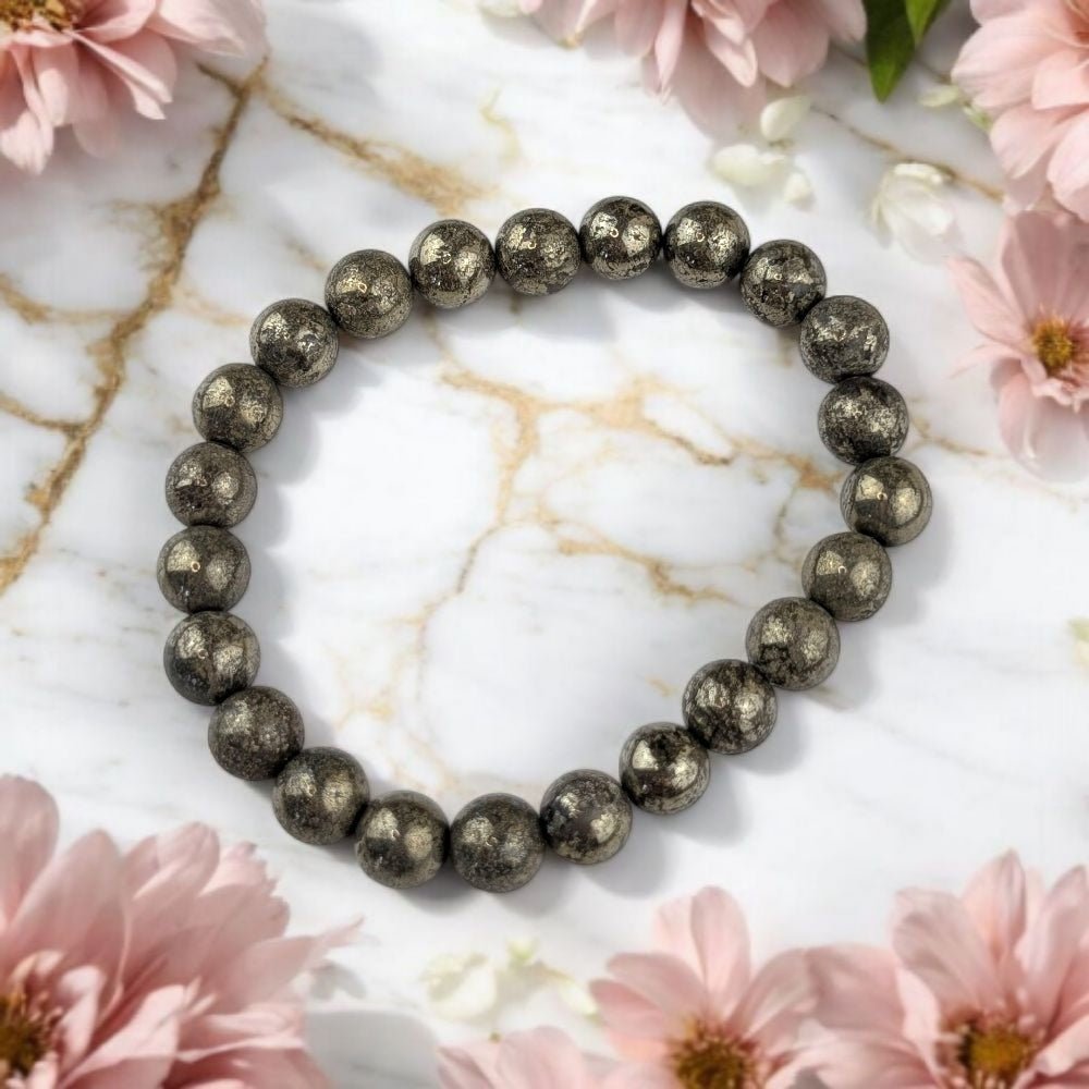 Pyrite beaded bracelet on a marble surface with pink flowers
