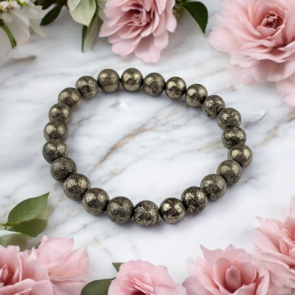 Pyrite beaded bracelet on a marble surface with pink flowers