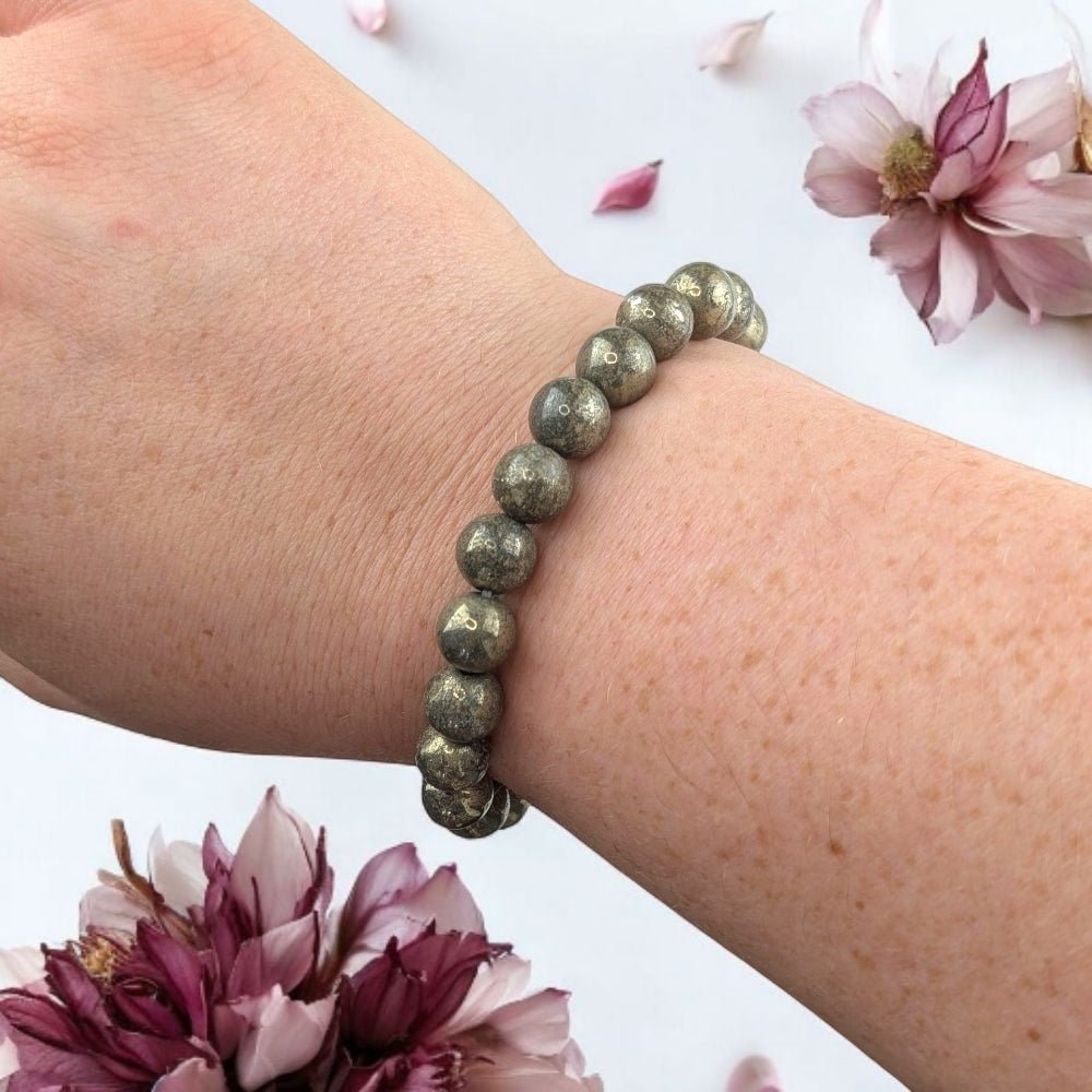 Beaded Pyrite crystal bracelet on a wrist with pink flowers in the background