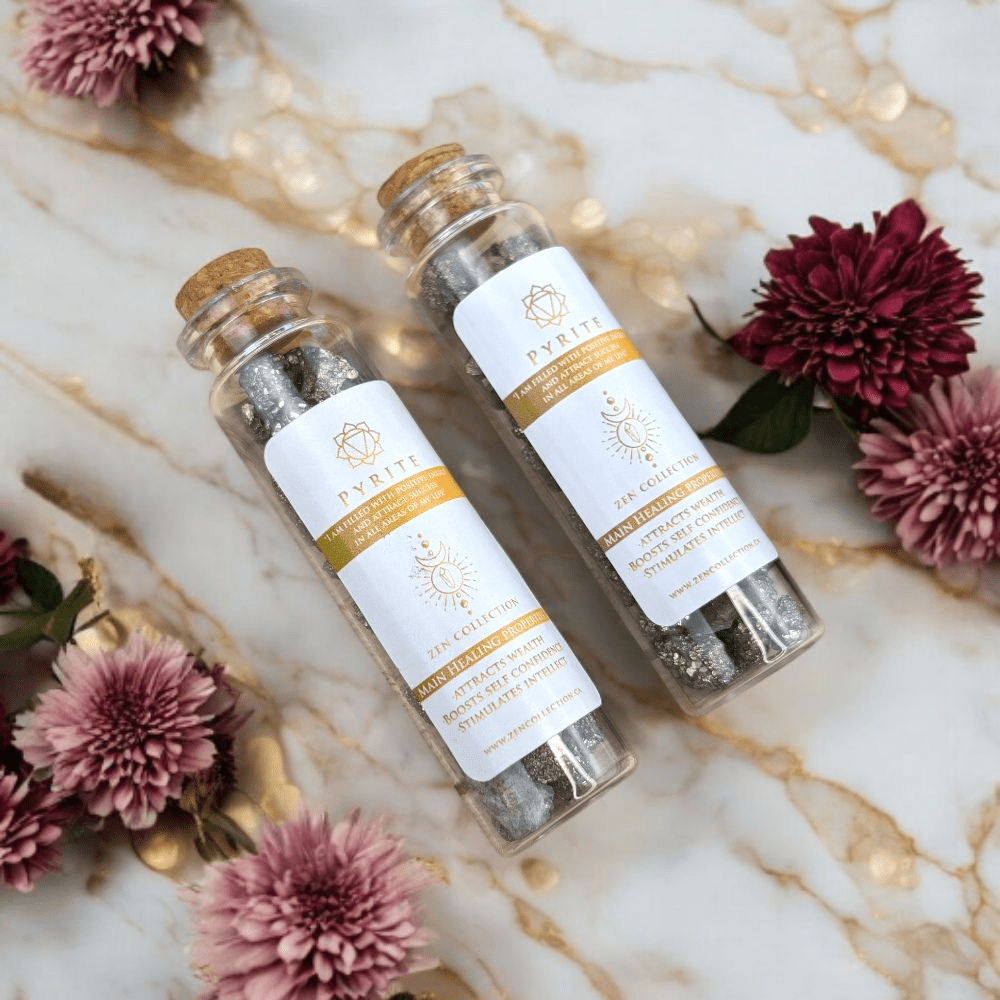Two glass jars filled with pyrite crystals with pyrite with cork lids on a marble surface with flowers